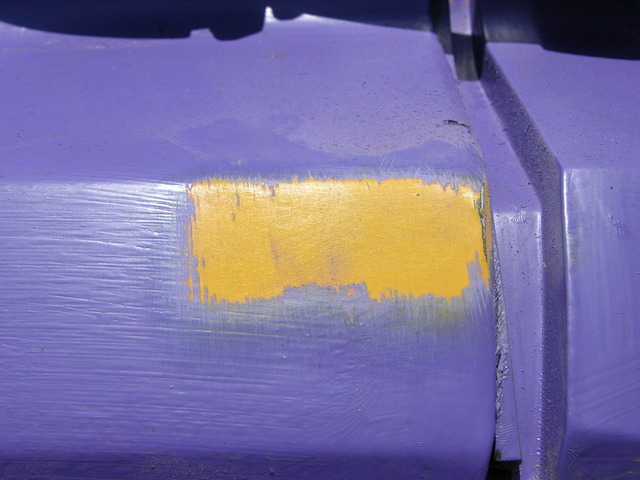 Purple house paint stripped from schoolbus fender, closeup