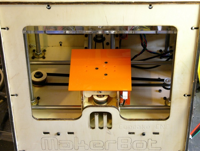 Orange acrylic sub-bed on MakerBot CupCake build stage